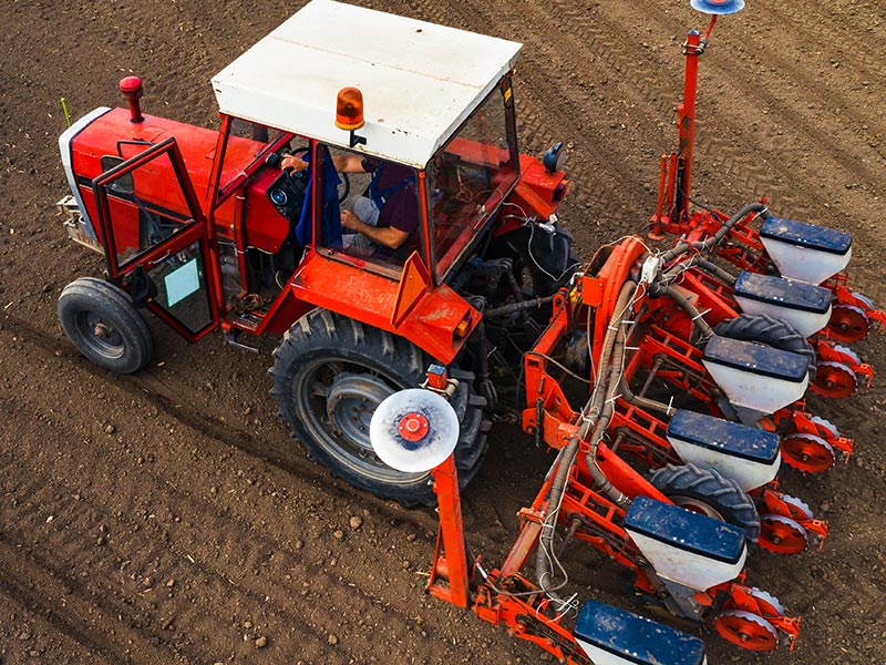A tractor tilling the soil of a piece of a farmland.