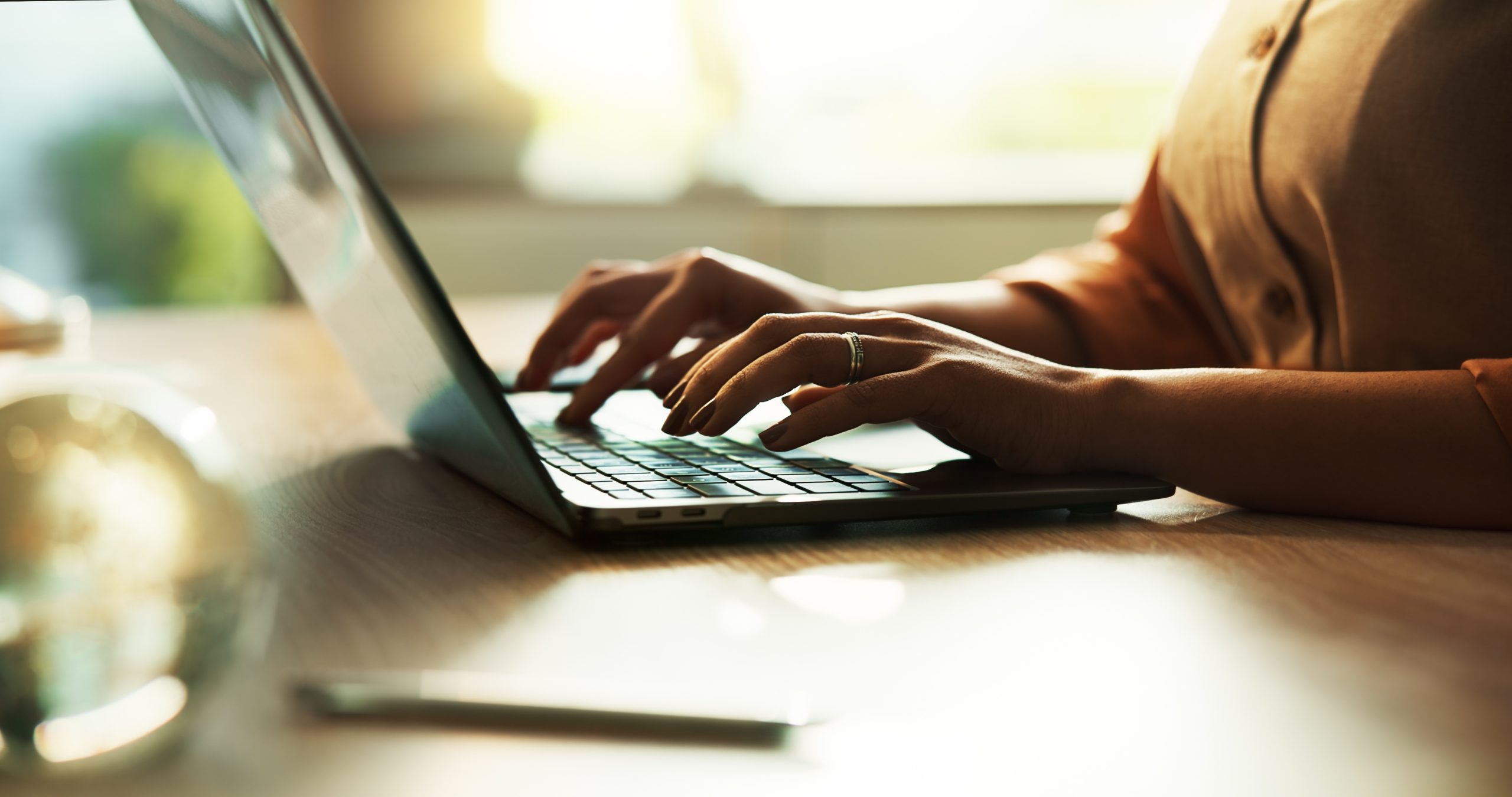 Closeup of a person's hands typing on a laptop.