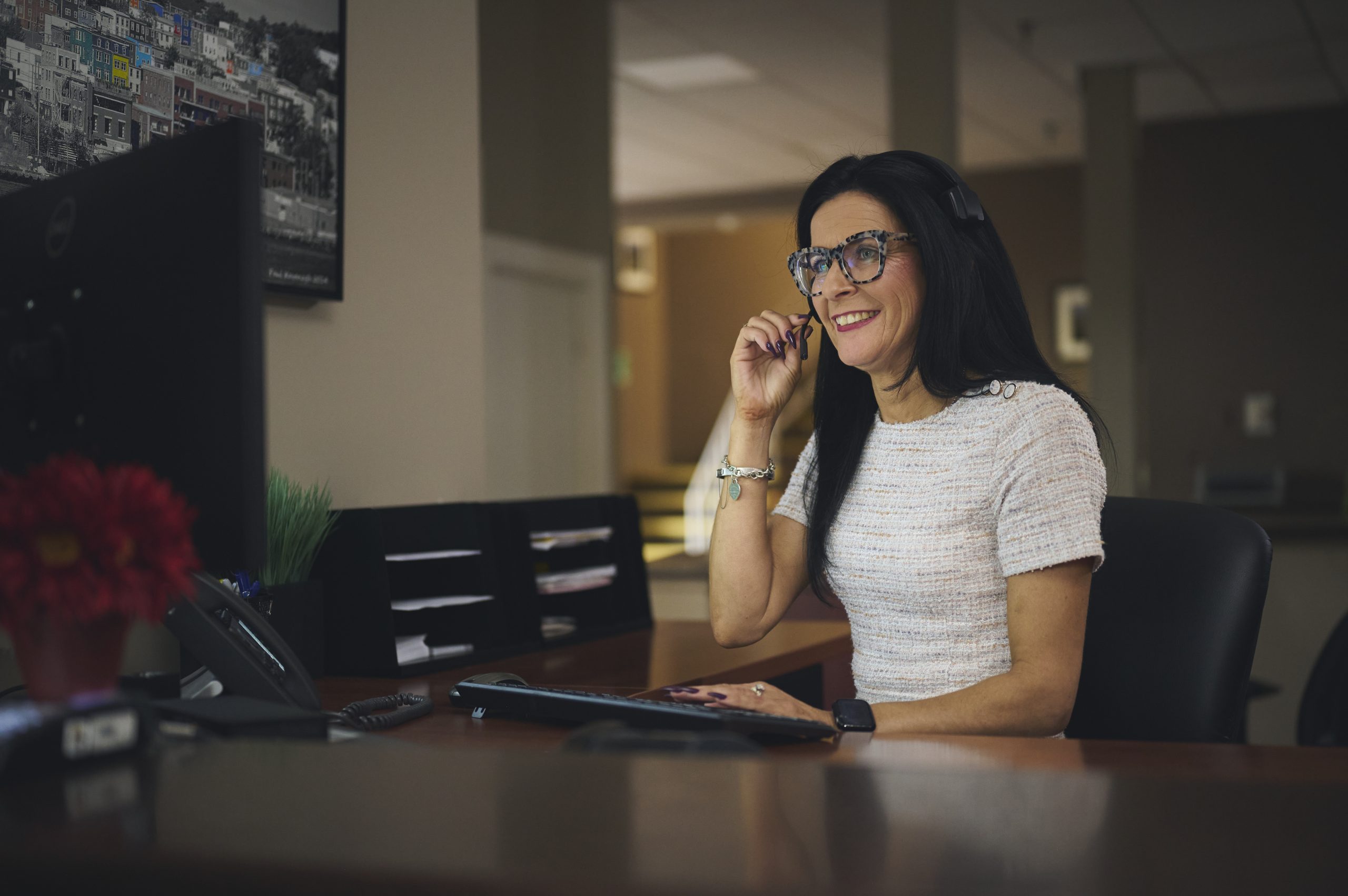 Harvey's receptionist sitting at the front desk, speaking with a customer through her headset with a friendly smile.