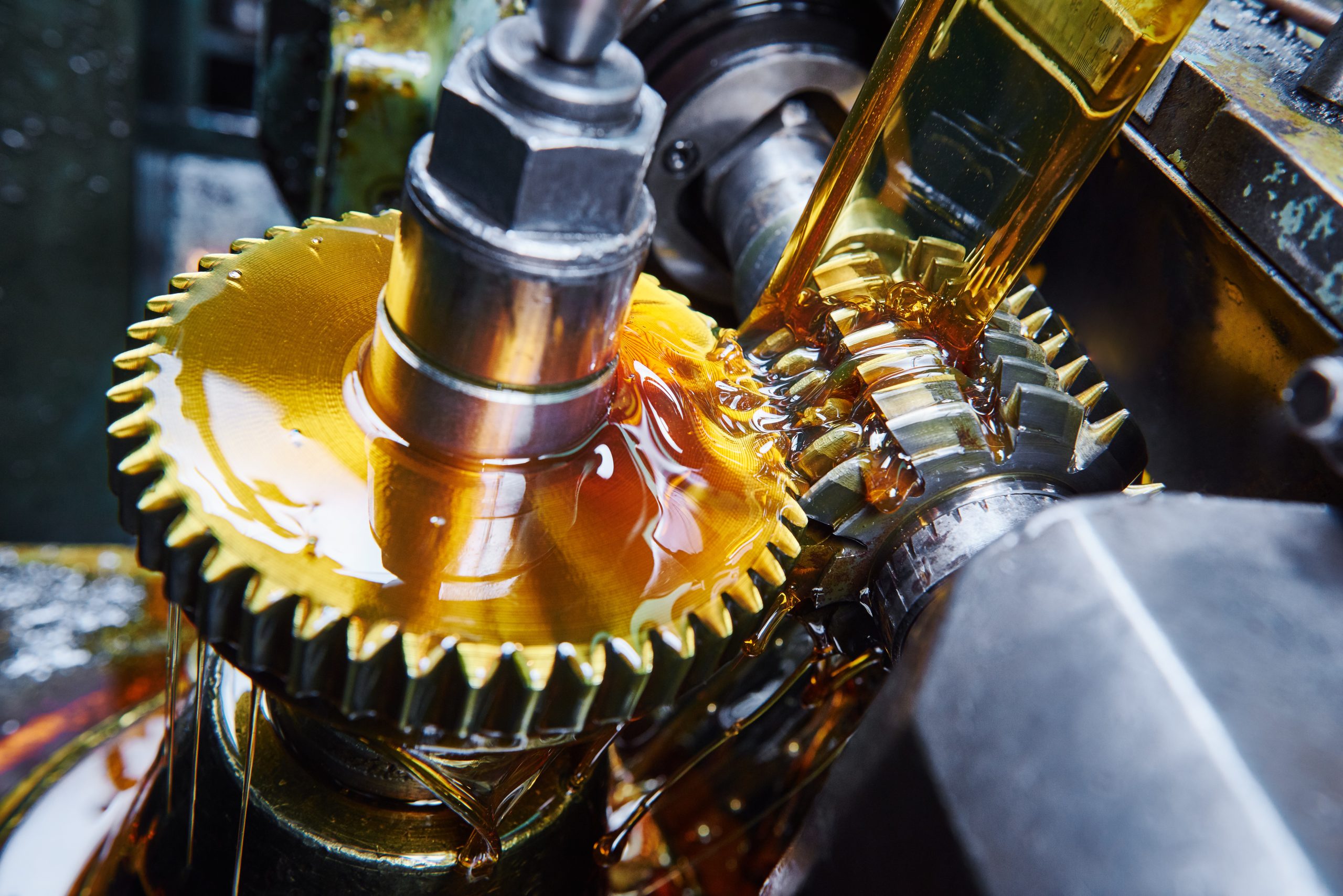 Metalworking gears and wheels being poured over with lubrication for smooth operation.
