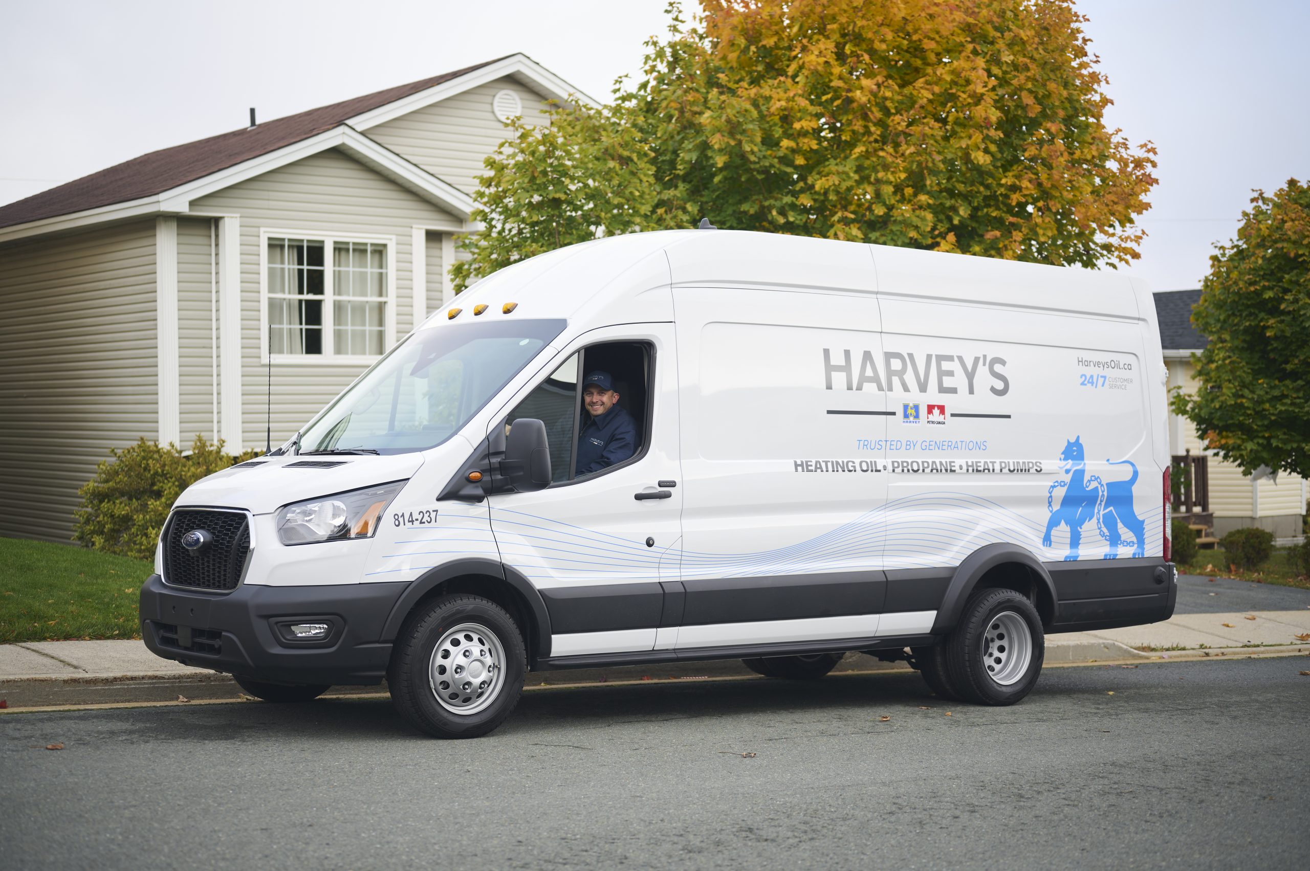 Harvey's service van, parked on the side of the road in a residential neighbourhood. The Harvey's employee behind the wheel gives a friendly smile.
