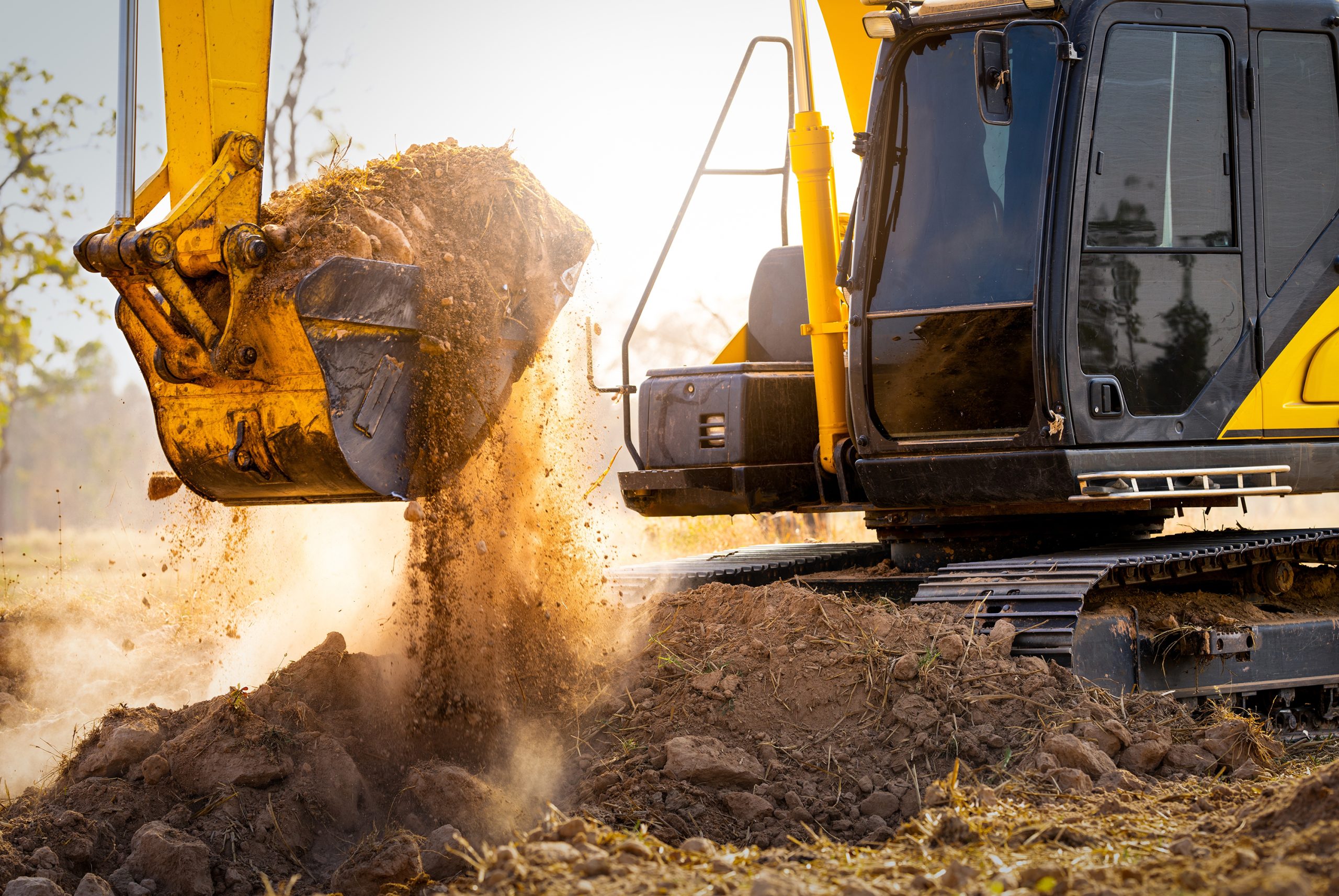 An excavator scooping up a large pile of dirt and soil at a construction site.