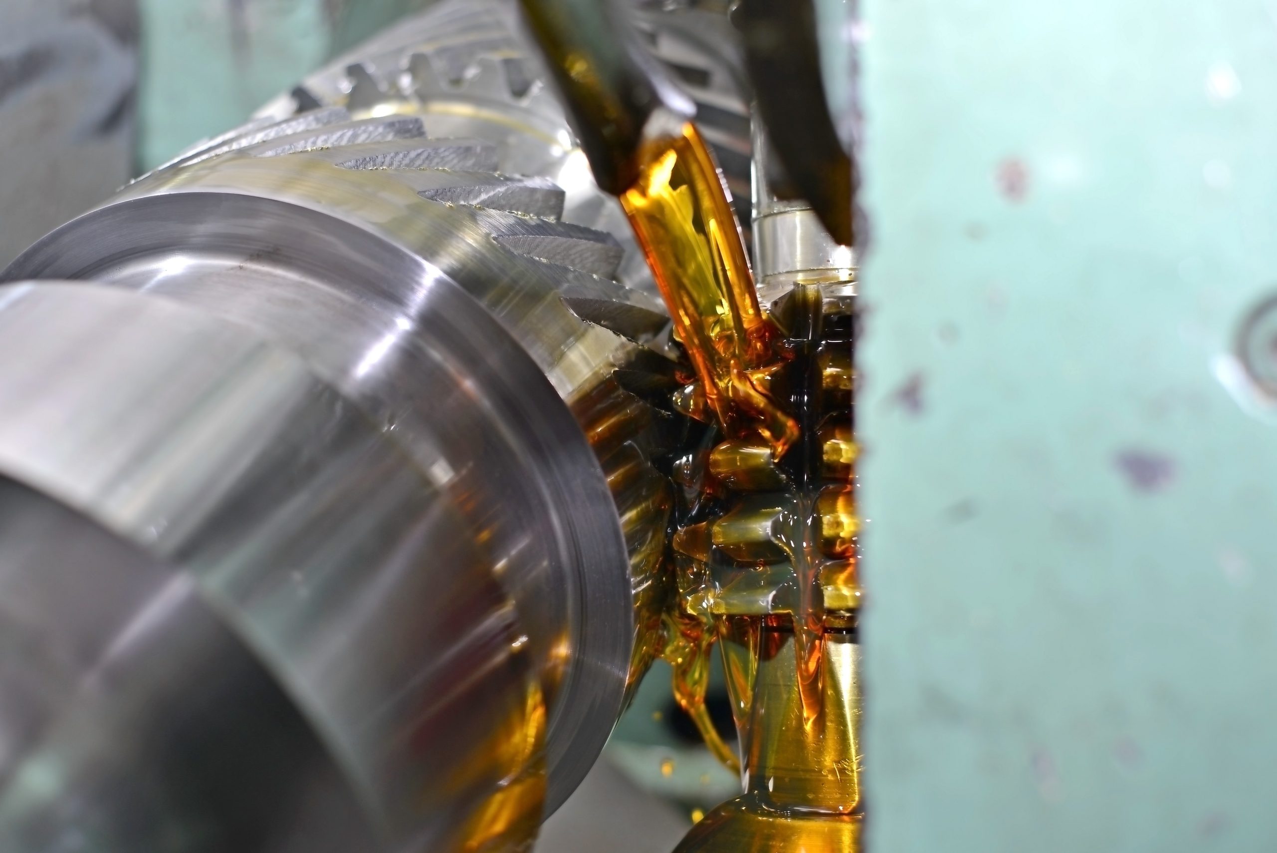 A gear-cutting machine being poured over with lubrication for smooth operation.